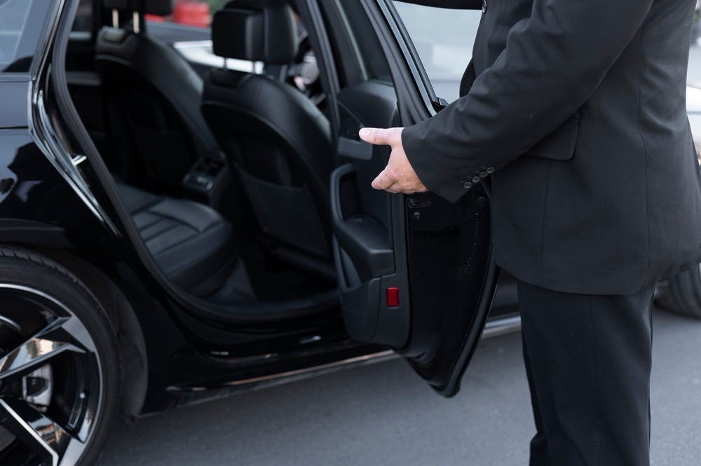 Chauffeur opening the door of a black luxury SUV